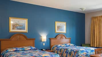 Habitación de hotel con dos camas, un escritorio, una silla, un teléfono y dos cuadros en la pared.