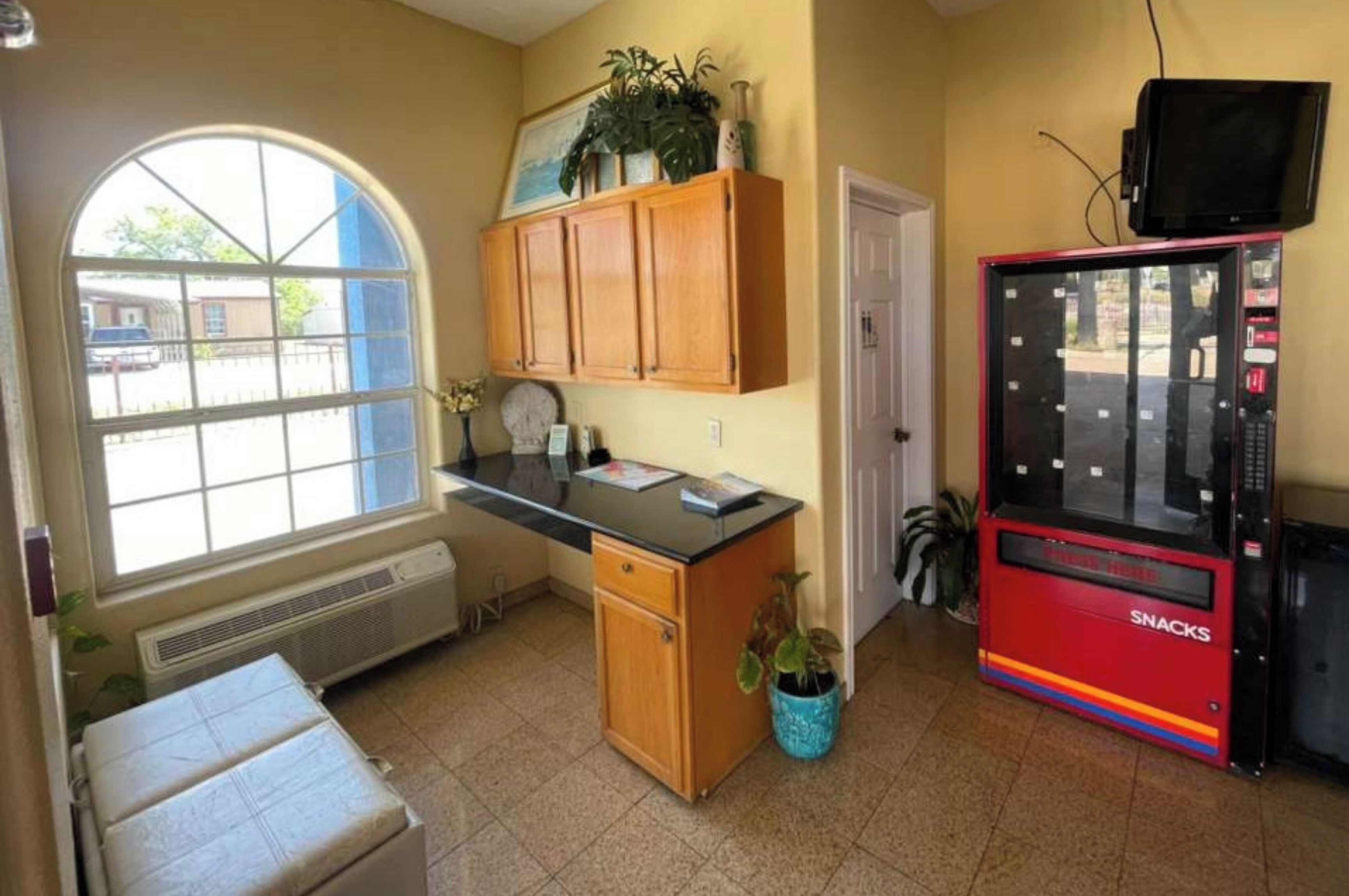 Una piccola cucina compatta con una finestra, una macchina distributrice e una porta.