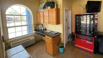 Una piccola cucina compatta con una finestra, una macchina distributrice e una porta.