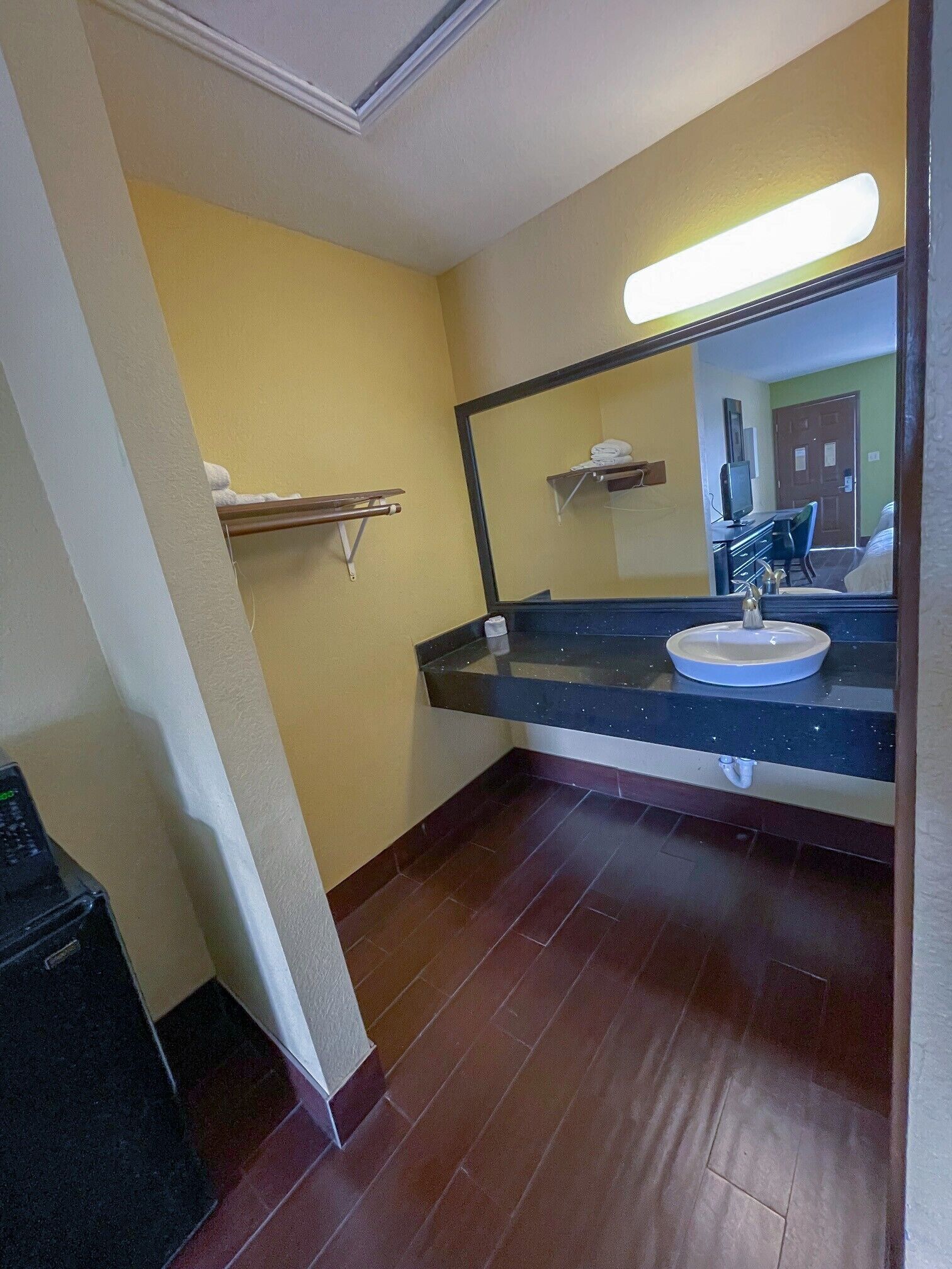 A bathroom with a sink, mirror, and towel rack.