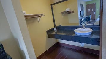 A bathroom with a sink, mirror, and towel rack.