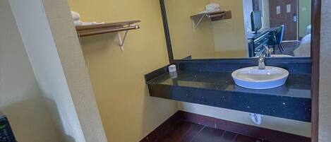 A bathroom with a sink, mirror, and towel rack.