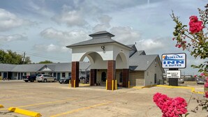 A hotel with a central archway entrance, a sign for a Delux Inn & Suites, and a sign indicating a vacancy and free internet. - Deluxe Inn & Suites Corpus Christi I 37 (Corpus Christi)