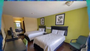 A hotel room with two beds, a desk, a chair, and a bathroom visible in the background. - Deluxe Inn & Suites Corpus Christi I 37 (Corpus Christi)
