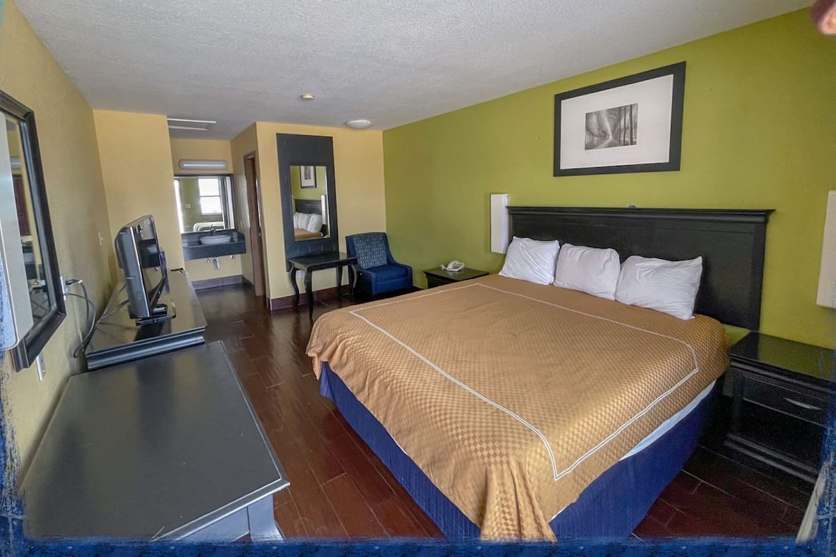 Habitación de hotel con cama, escritorio, silla y un cuadro en la pared.