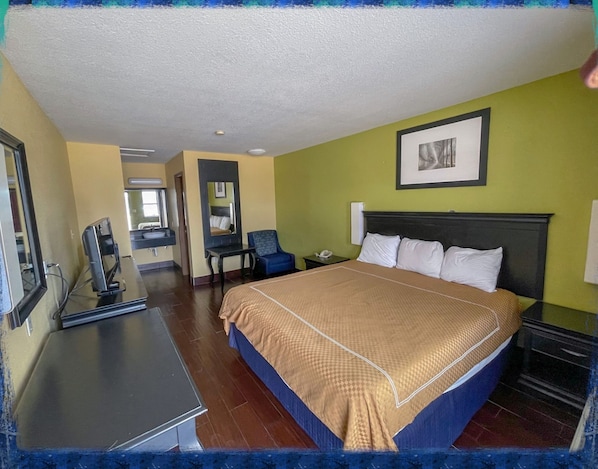 A hotel room with a bed, desk, chair, and a framed picture on the wall. - Deluxe Inn & Suites Corpus Christi I 37 (Corpus Christi)