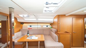 Un intérieur compact et bien éclairé, comprenant un coin salon, une table avec une bouteille et des verres, et une porte.