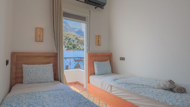 Une chambre avec deux lits, une fenêtre donnant sur les montagnes et un appareil de climatisation.