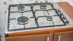 Une cuisinière à gaz avec quatre brûleurs, un bouton de commande et le nom de la marque « Candy » sur le côté droit.