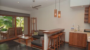 Um espaço moderno para viver, com sofá, cadeiras de madeira, área de refeições e cozinha.