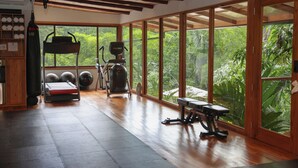 Uma academia com equipamentos de ginástica, janelas amplas e piso de madeira.