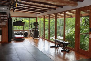 Ein Fitnessstudio mit Trainingsgeräten, großen Fenstern und Holzboden.