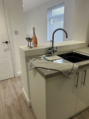 A modern kitchen with a built-in sink, a window with blinds, and a door.