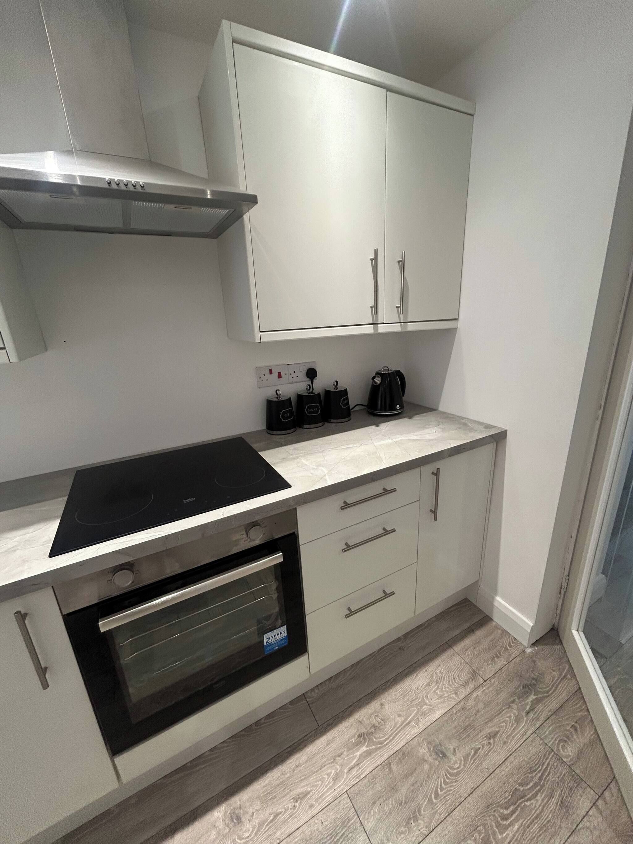 Cocina compacta con horno integrado, placa de cocina y cafetera.