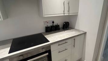 Cocina compacta con horno integrado, placa de cocina y cafetera.