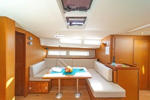 A compact boat interior with a dining area, seating, and a small kitchenette.