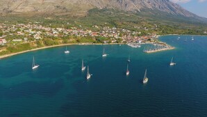 An aerial view of a coastal town with a marina, boats, and mountainous backdrop. - Sun-Kissed Sailing Adventure in the Ionian Islands (Paleros)