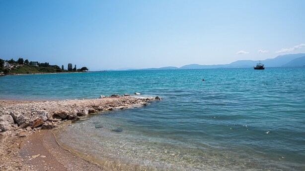 A clear coastal view with a rocky shoreline, calm sea, and distant mountains. - Sun-Kissed Sailing Adventure in the Ionian Islands (Paleros)