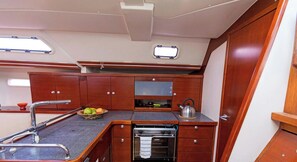 A compact kitchen with wooden cabinets, a built-in oven, and a small window. - Sun-Kissed Sailing Adventure in Islas Sarónicas (Piraeus)