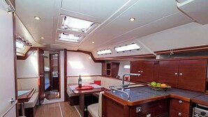 A compact kitchen with a dining area, a small sink, and a window above the counter. - Sun-Kissed Sailing Adventure in Islas Sarónicas (Piraeus)