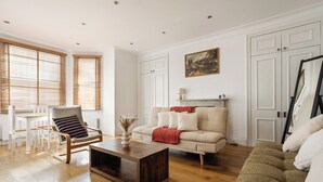 Een woonkamer met een bank, fauteuil, salontafel en een schilderij aan de muur.