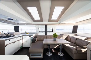 Ein modernes Yacht-Interieur mit Küche, Sitzgruppe und großen Fenstern mit Blick auf den Ozean.