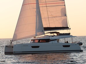 Eine Segelyacht namens 'Vienna Pearl' mit Kabine und Deckssitzgelegenheiten, die auf ruhigem Wasser segelt.