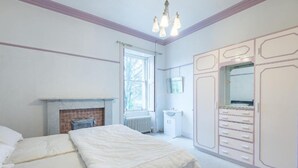 A bedroom with a bed, a fireplace, a window, a wardrobe, and a mirror. - OYO Ashlea Manor (Dundee)