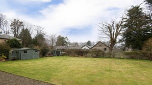 A residential property with a large grassy yard, a small shed, and a stone wall. - OYO Ashlea Manor (Dundee)