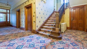 A grand staircase with ornate railings, a patterned carpet, and wooden doors. - OYO Ashlea Manor (Dundee)