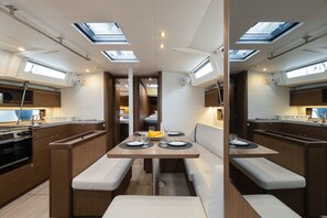 A compact kitchen with a central dining table, built-in appliances, and skylights.