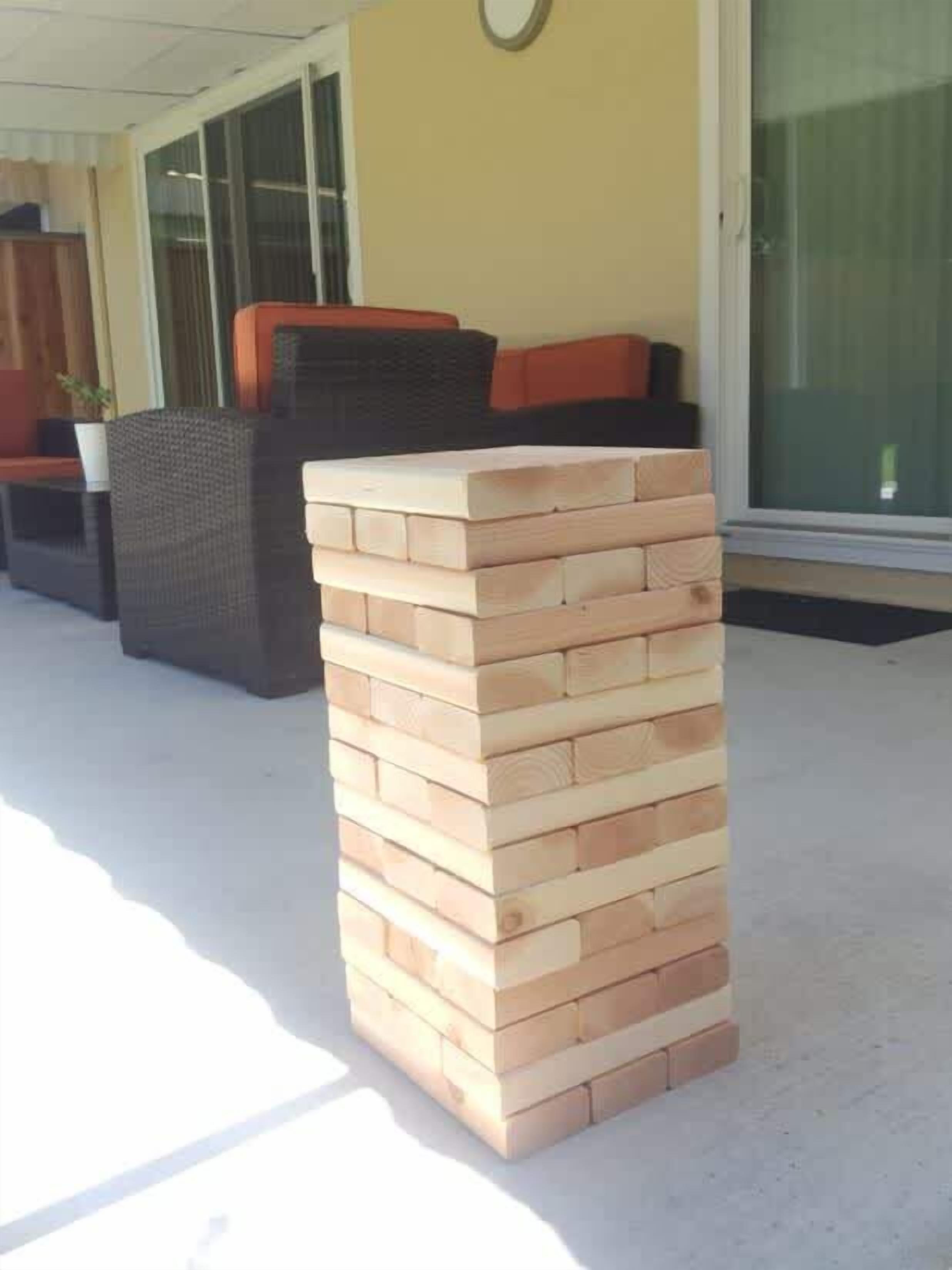 A stack of wooden blocks outdoors, a wicker sofa, and a glass door in the background.
