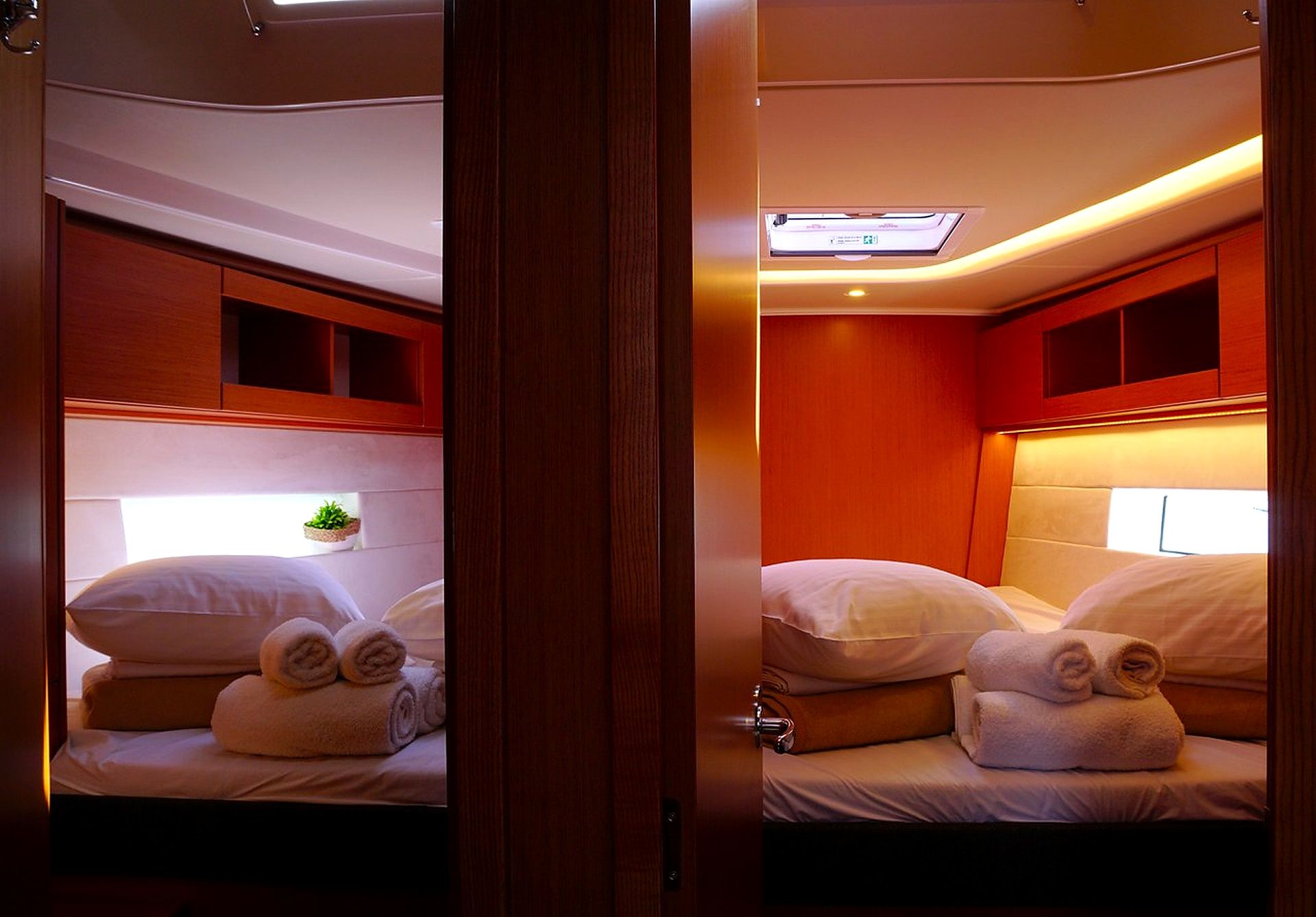 A cabin with two beds, each with a headboard, a small shelf, and a window.