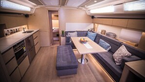 A compact kitchen with a dining area, a bench, and a sofa with cushions. - Sun-Kissed Sailing Adventure in the Saronic Islands (Laurium)