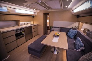 A compact kitchen with modern appliances, a dining table, and a sofa with cushions. - Sun-Kissed Sailing Adventure in the Saronic Islands (Laurium)
