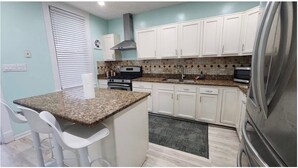 A kitchen with white cabinets, a granite countertop, a stove, and a refrigerator. - Luxurious 4BR Home Newly Renovated Churchill Downs (Louisville)