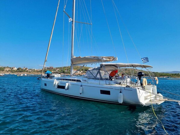 A sailboat with a cabin, a flag, and a person on deck. - Sun-Kissed Sailing Adventure in the Saronic Islands (Laurium)