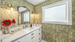 A bathroom with a vanity, mirror, and floral wallpaper.