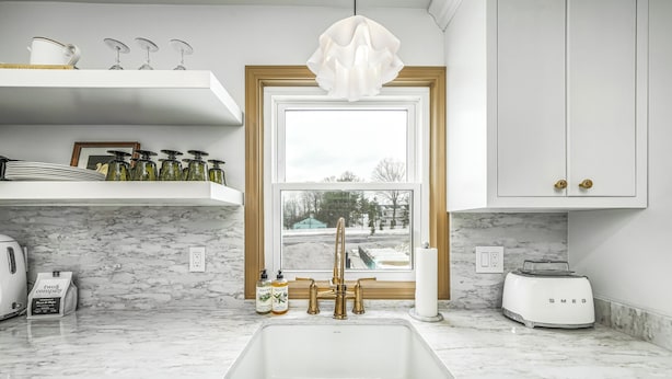 A kitchen with a white sink, a window with a view, and a white countertop.