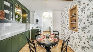 A dining area with a round table, chairs, and a hanging light fixture.