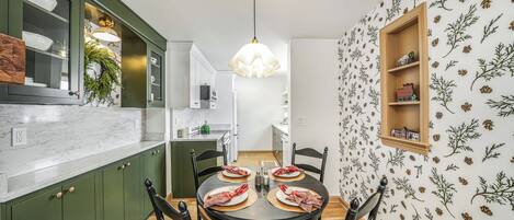 A dining area with a round table, chairs, and a hanging light fixture.