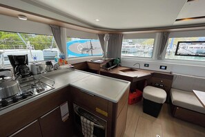 Een kleine keuken met een kookplaat, spoelbak en een eethoekje.