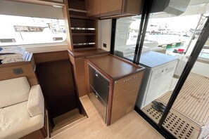 A compact kitchen area with a refrigerator, a sink, and a window providing a view of the marina.