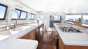 A modern kitchen with white countertops, wooden cabinets, and a central island. - Sun-Kissed Sailing Adventure in the Saronic Islands (Palaio Faliro)