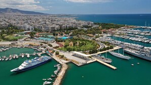 A marina with multiple boats, a large cruise ship docked, and a cityscape in the background. - Sun-Kissed Sailing Adventure in the Saronic Islands (Palaio Faliro)