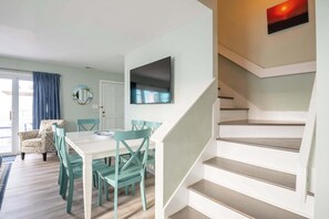 Ein modernes Interieur mit Essbereich, Treppe und einem an der Wand befestigten Flachbildfernseher.