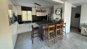 Eine moderne Küche mit einer großen Kochinsel, Barhocker und einem Essbereich.