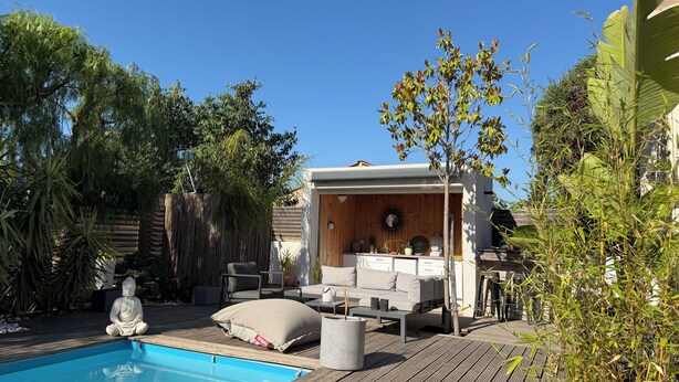 Ein Poolbereich mit Holzterrasse, einer Meditationsstatue, einer überdachten Sitzgelegenheit mit Kissen und einem kleinen Tisch.