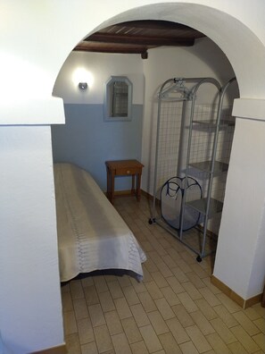 Ein kleines Zimmer mit Etagenbett, Tisch und einem Metallregal.