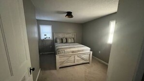 Un dormitorio con cama, ventana y puerta.
